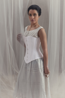 Femme vêtu d'une jupe gris clair et d'un corset 1880 blanc.